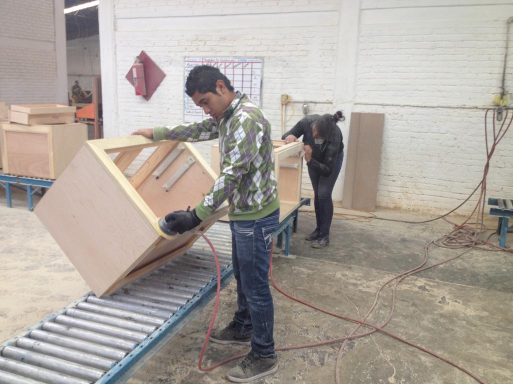 Worker sanding furniture in production line